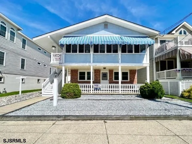We see the front of a white and blue condo in Ocean City, NJ against a clear blue sky.