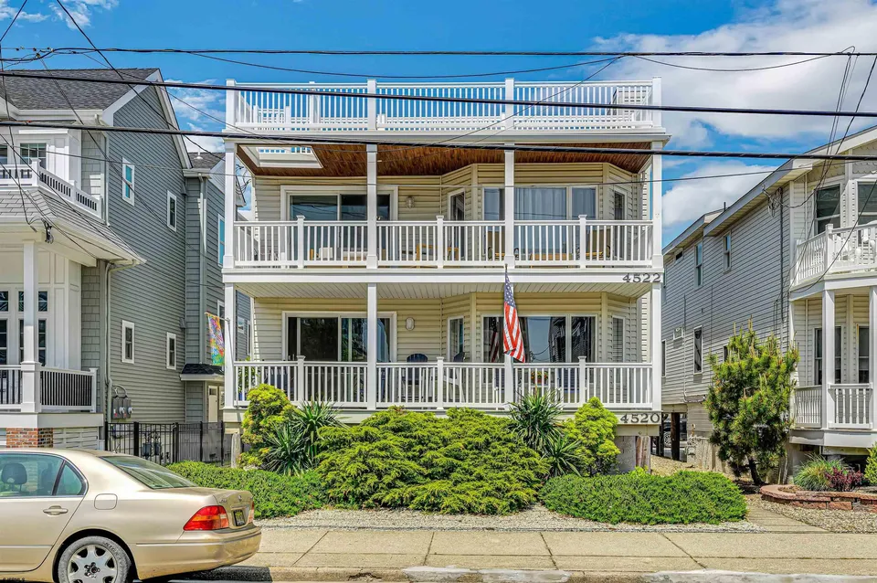 We see the front of a beige Ocean City, NJ house against a clear blue sky.