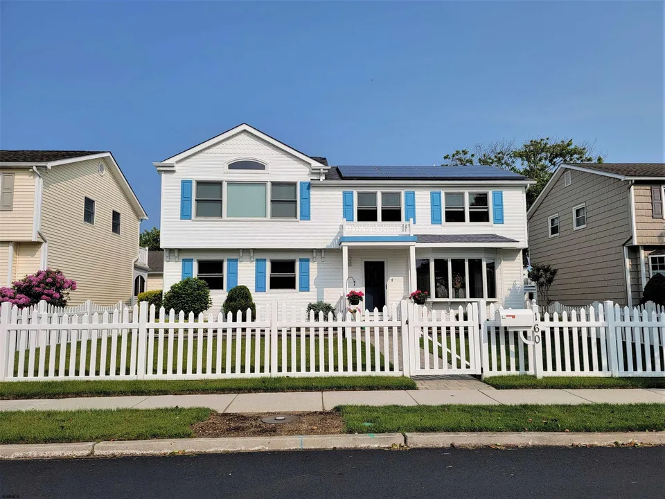 We see the front of a white single-family home adorned with blue shutters in Ocean City, NJ.