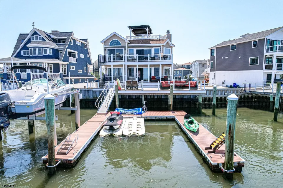 We see the front of a beige house on the water in Ocean City, NJ against a clear blue sky. The home's boat slip is in view as well.