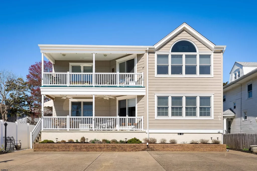 We see the front of a beige, two-story house in Ocean City, NJ against a clear blue sky.