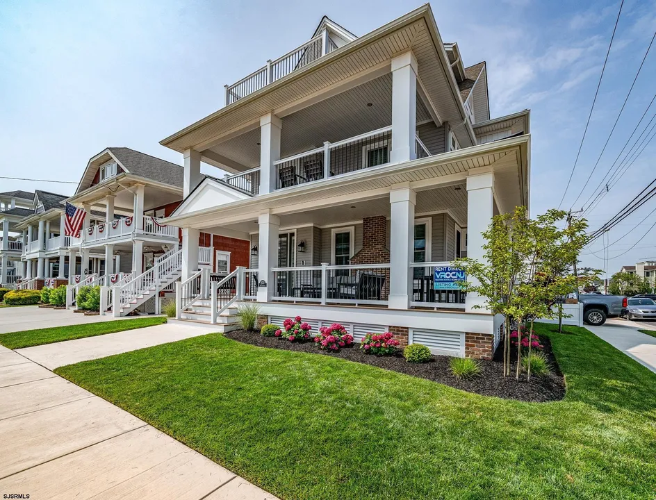 We see the front of a two-story, white house in Ocean City, NJ in front of a freshly cut green lawn.