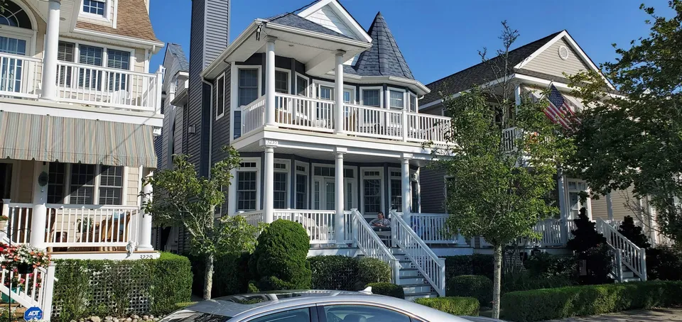 We see a street-side view of a blue and white house in Ocean City, NJ during the day.